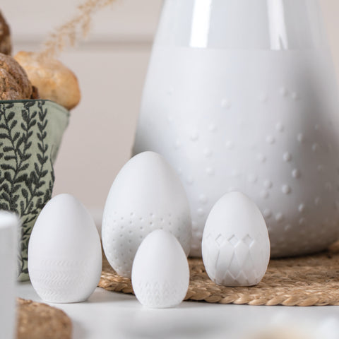 White Porcelain Easter Eggs Embossed on a table with a vase and placemat.