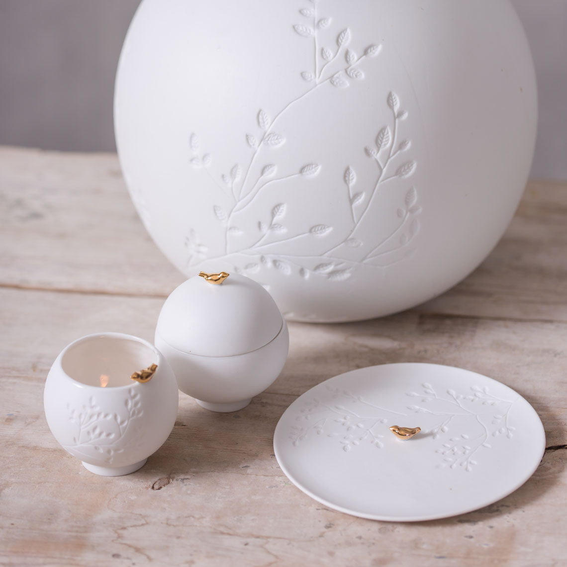 Set of white ceramic items with embossed designs on a wooden surface