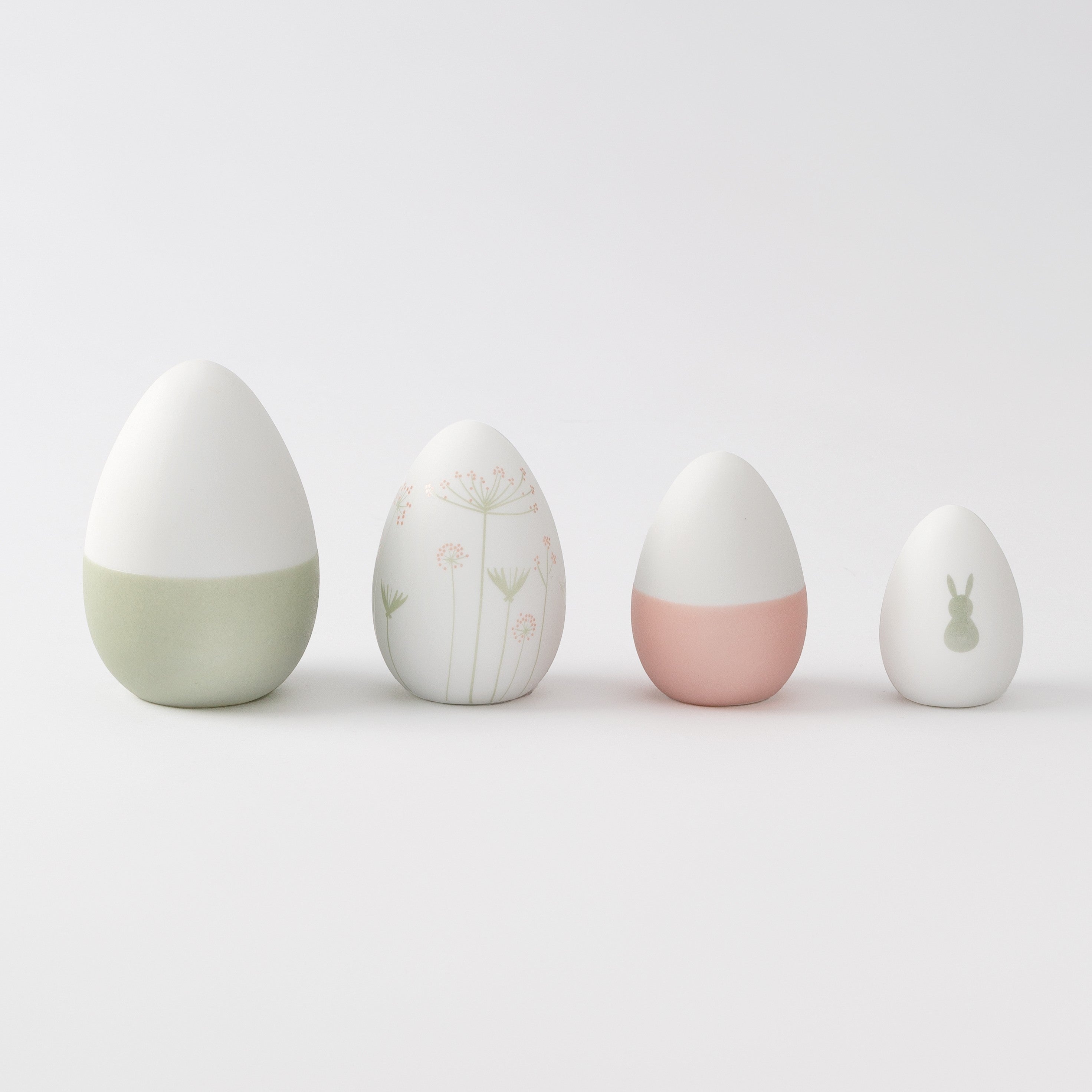 R17462 Four porcelain Easter decorative eggs with different designs on a light gray background