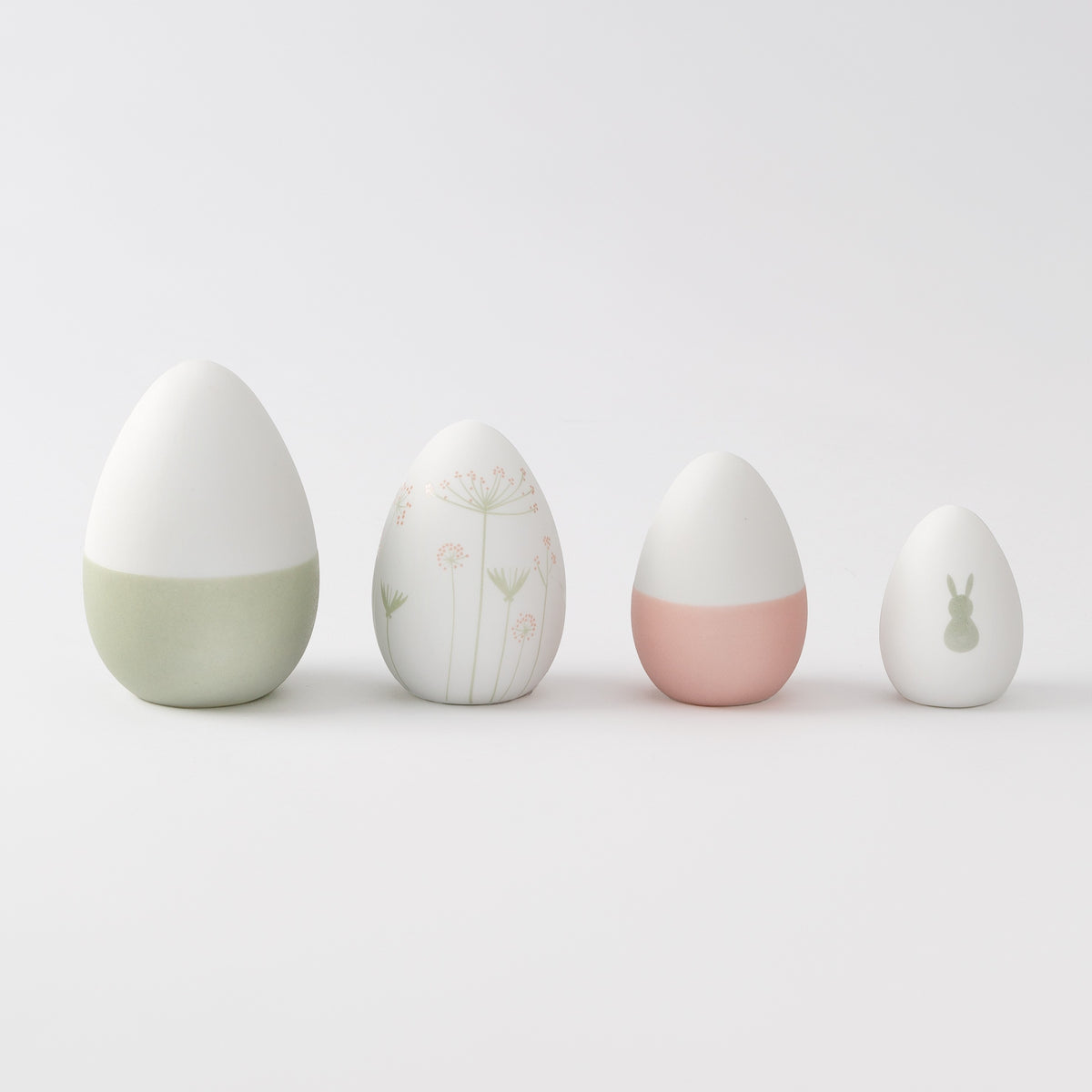 R17462 Four porcelain Easter decorative eggs with different designs on a light gray background