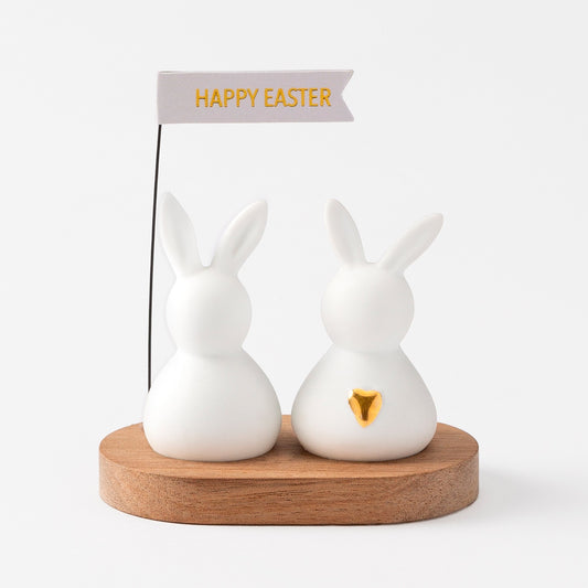 R17463 Two porcelain bunnies on an acacia wood tray holding a happy easter sign.