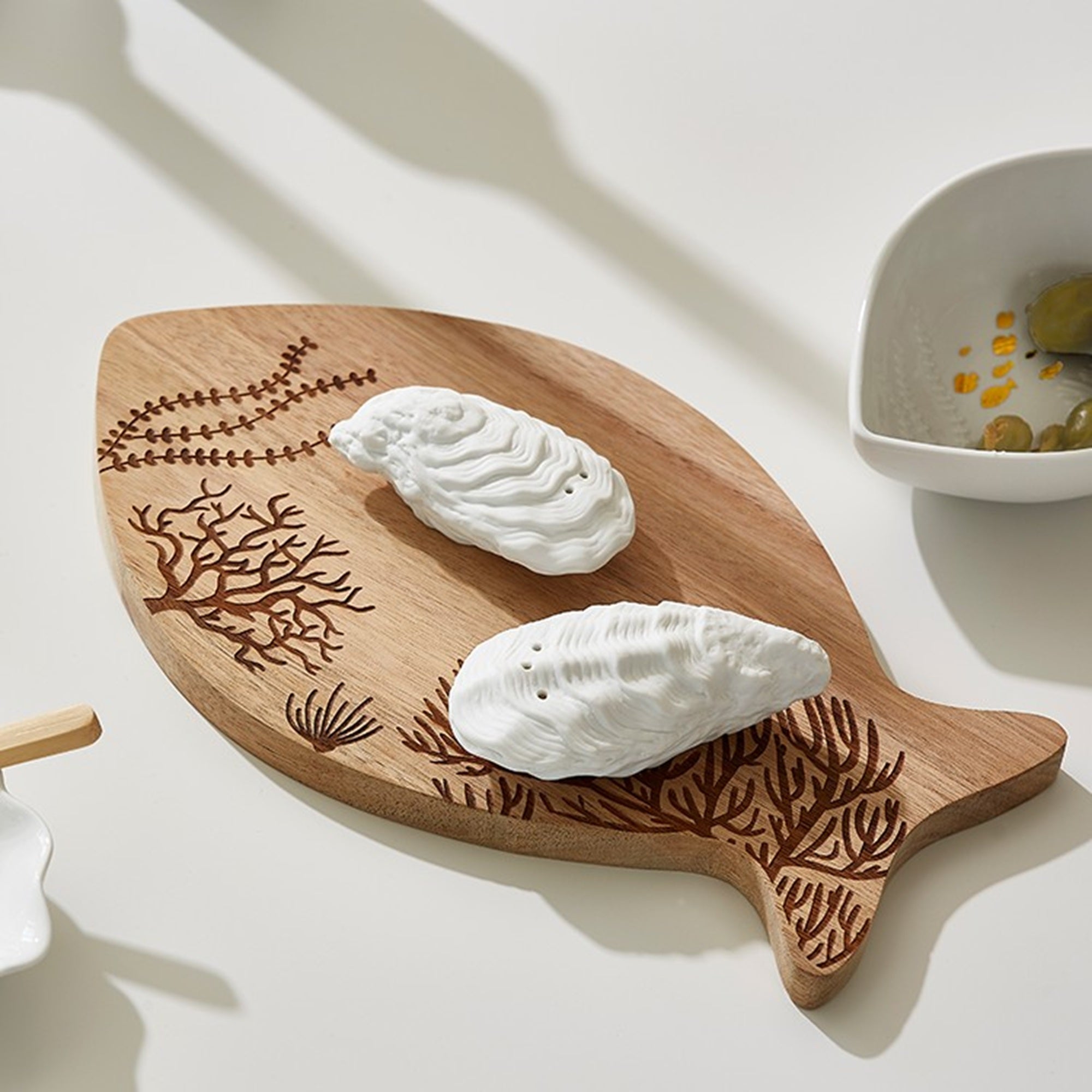 Porcelain Coastal Oyster Salt and Pepper Shaker Set on fished shaped cutting board in a kitchen setting