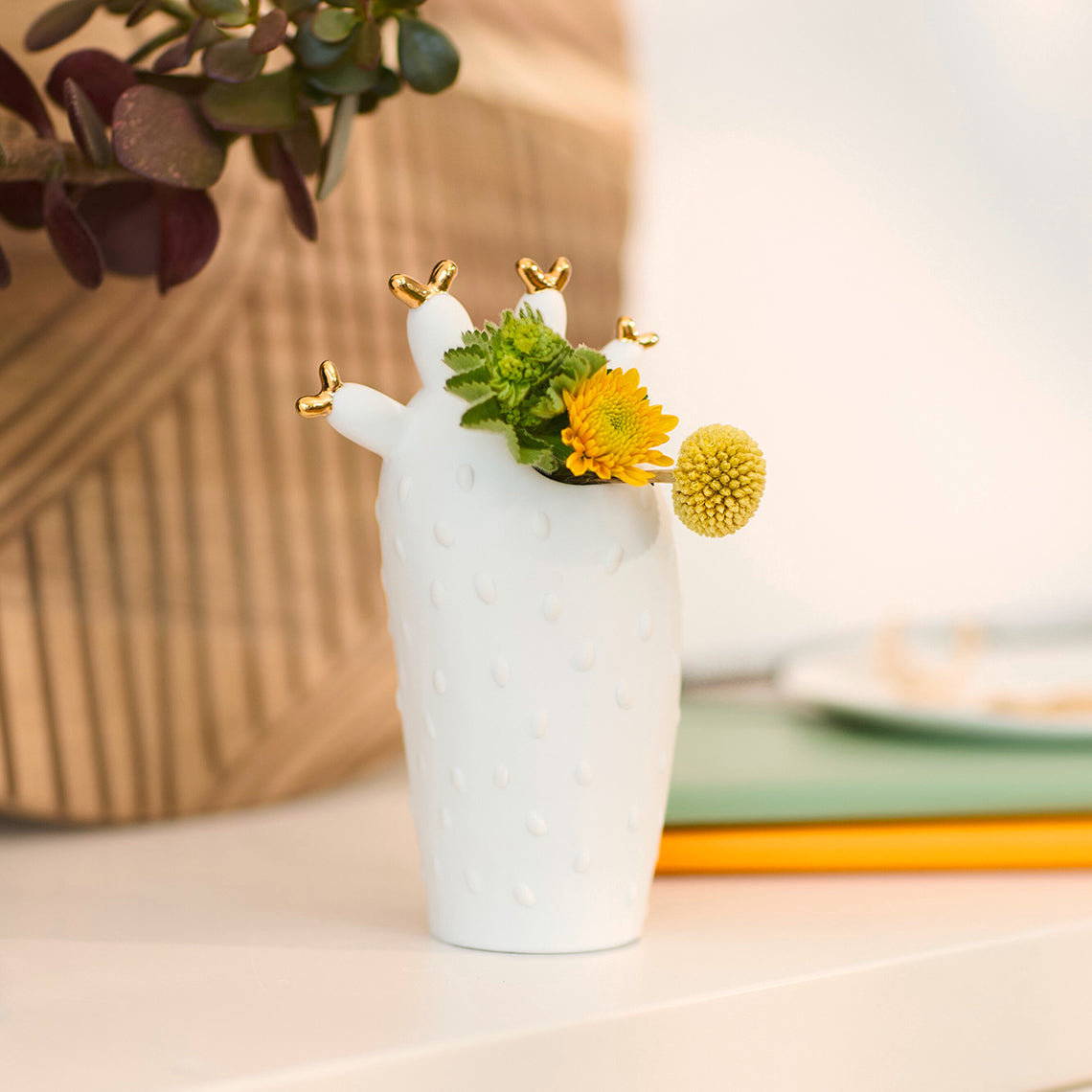 White ceramic cactus-shaped vase with flowers on a table