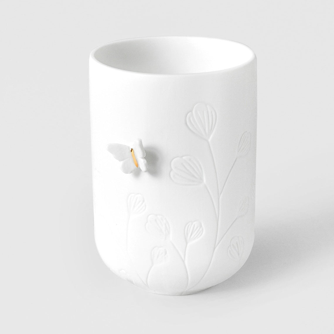 R17619 White porcelain tealight holder with embossed butterfly and floral design on a light gray background