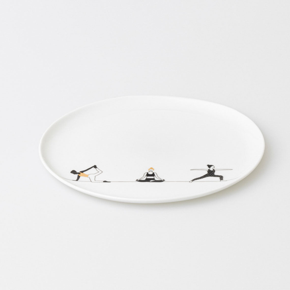 White porcelain plate with black illustrations of people doing yoga on a white background
