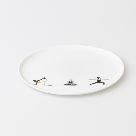 White porcelain plate with black illustrations of people doing yoga on a white background