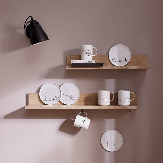Wooden shelves with porcelain plates and mugs against a beige wall.