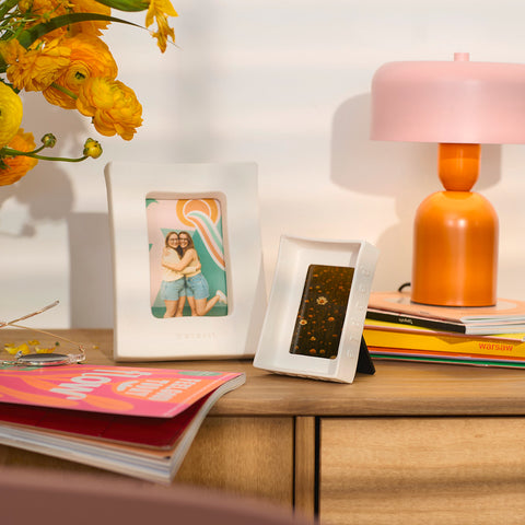 Wooden surface with a lamp, photo frames, and books on a light background
