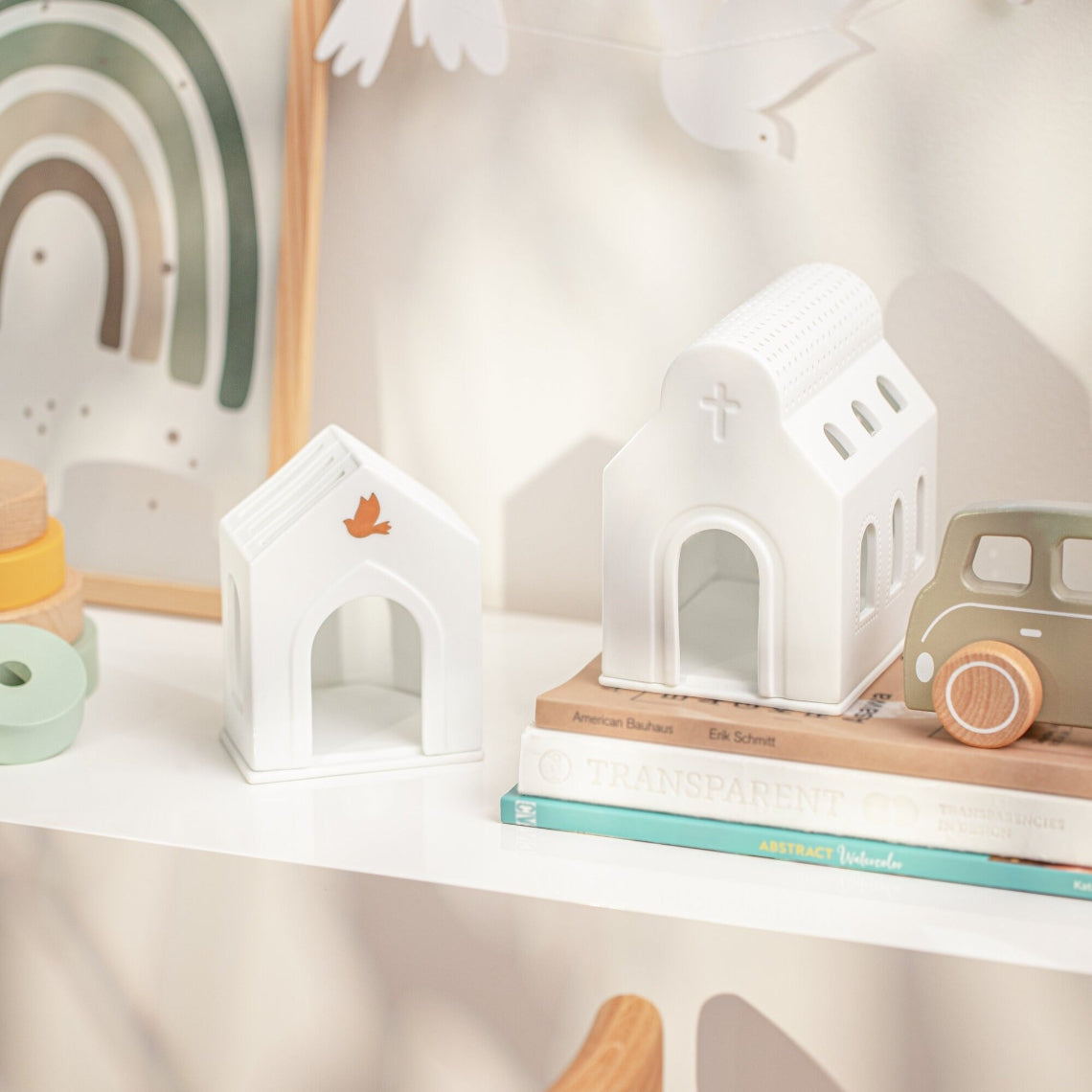 Porcelain Village Houses on a shelf with children's toys and books. 
