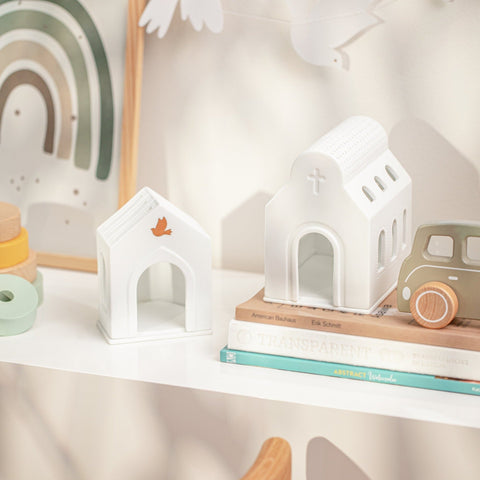 Porcelain Village Houses on a shelf with children's toys and books. 