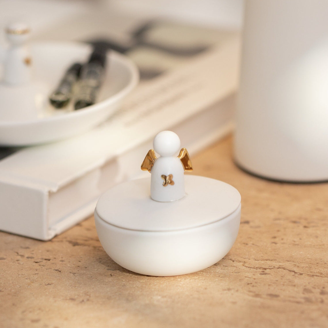 White ceramic ring holder with angel design on a wooden surface
