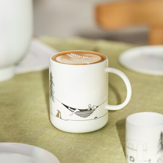 White mug with a design on a green tablecloth