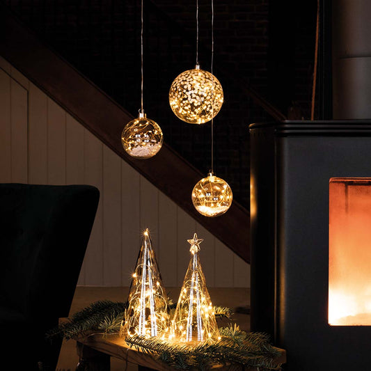 Glass Christmas Trees with LED Lights with holiday decor in the background.