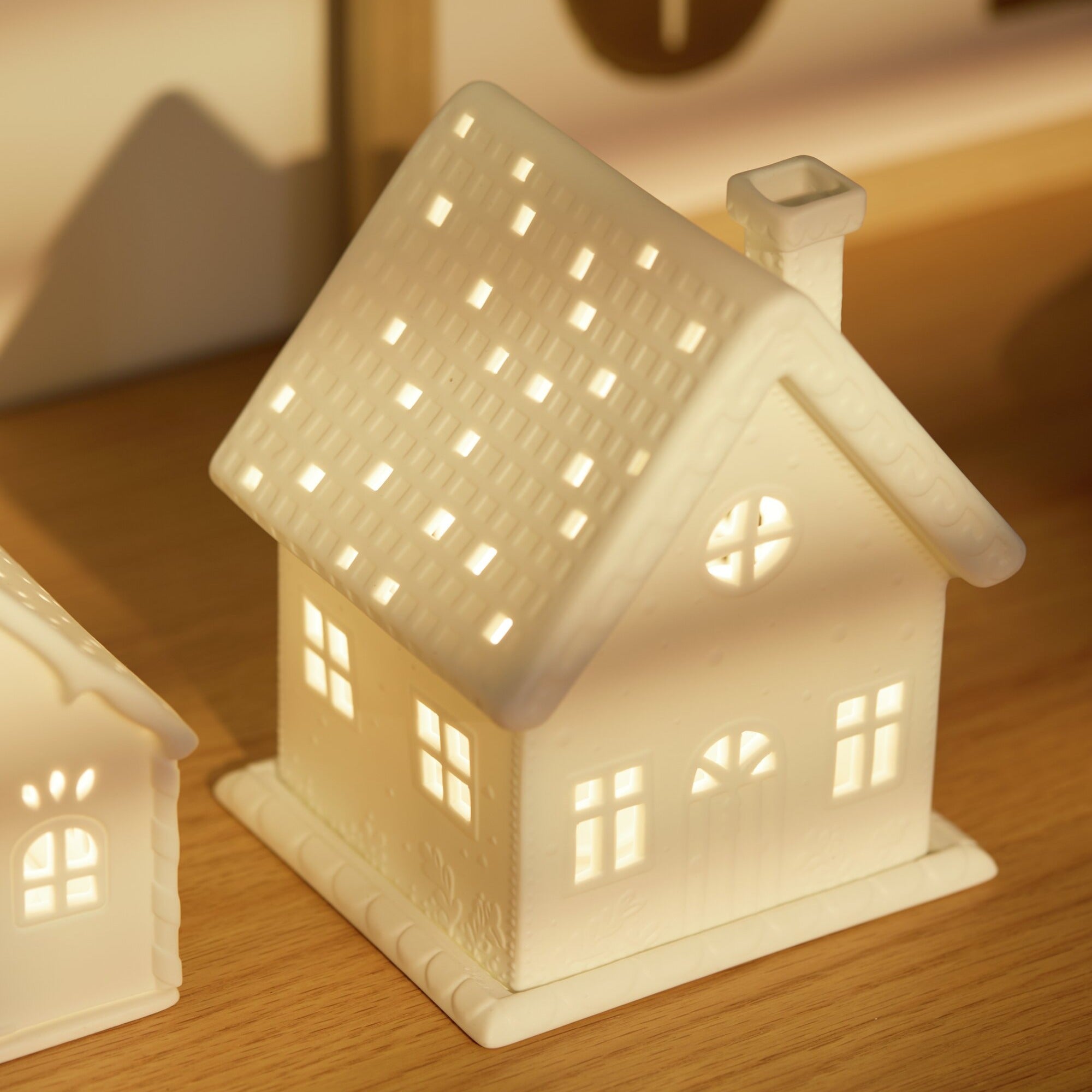 Village House Winter Cottage Porcelain Tealight House with Christmas Vine Decor lit from within with a tealight.
