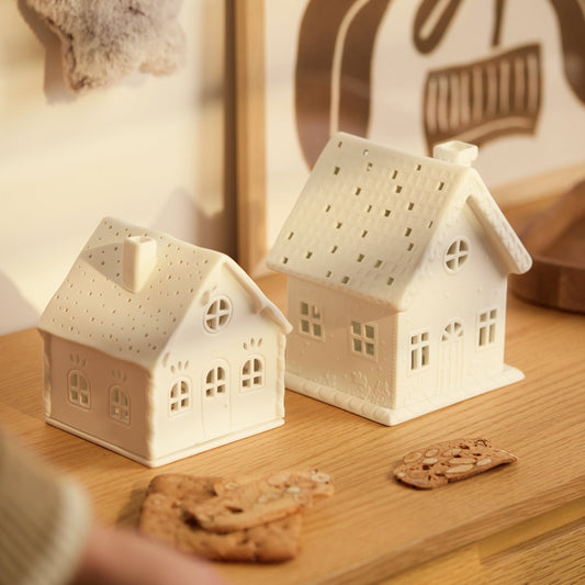 Village House Winter Cottage Porcelain Tealight Houses on a wood countertop with Christmas decor.