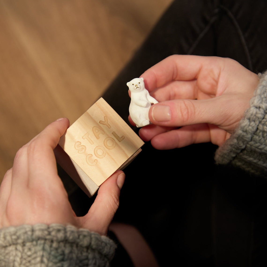 Person holding a small white polar bear figurine and a wooden box with engraved text.